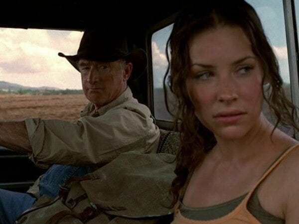 Kate Austin (Evangeline Lily) looks out the window nervously. In the driver's seat, the Australian farmer who is giving her a ride favors her with a suspicious glance.