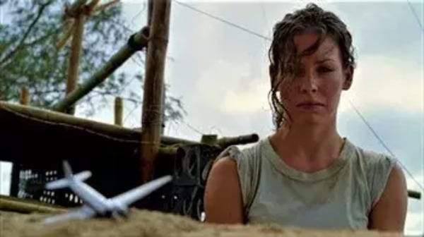 Kate Austen (Evangeline Lilly) looks sadly at her toy airplane, which is embedded in the sand of the beach.