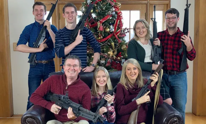 Representative Thomas Massie and his family pose for a Christmas photo, holding massacre weapons.